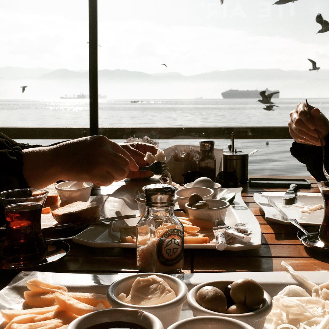 people at a table with plates of food overlooking the ocean